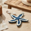 Starfish-shaped keychain on a wooden surface with a shell