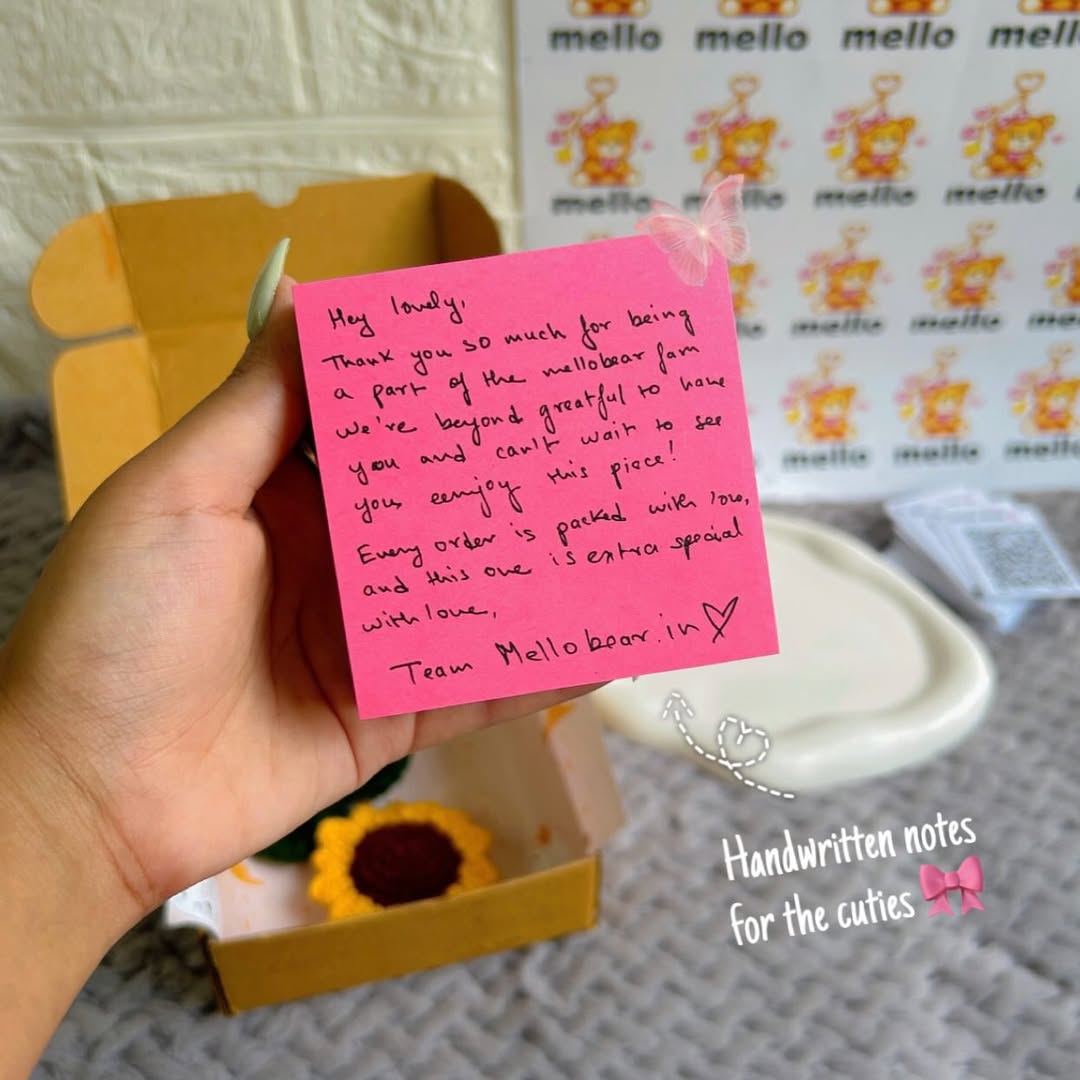 Handwritten note on a pink post-it held by a hand, with a branded background.