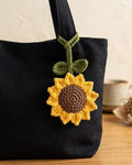 Black tote bag with a sunflower-shaped patch on a wooden surface.