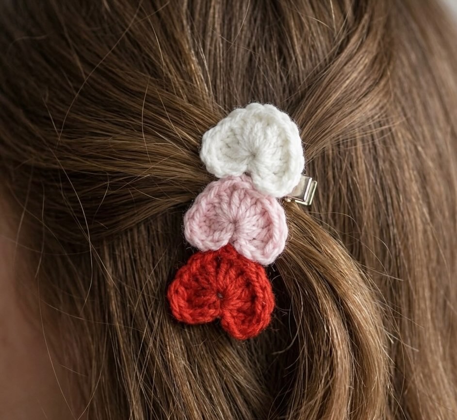 Crocheted hair clip with red, pink, and white flowers in brown hair