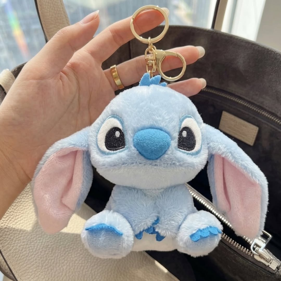 Plush keychain shaped like a cartoon character held by a hand.