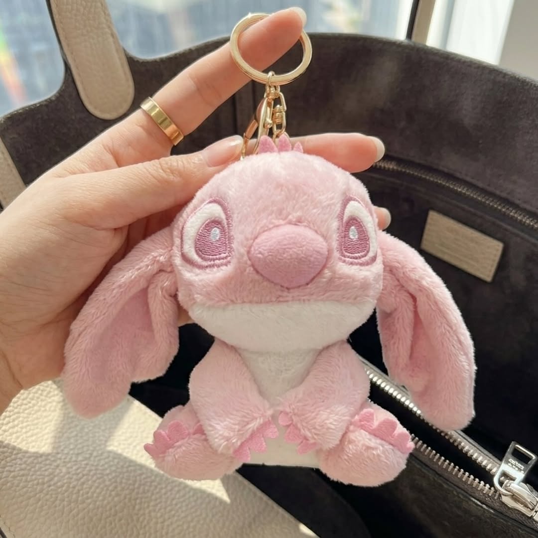 Pink plush keychain held by a hand with a blurred background