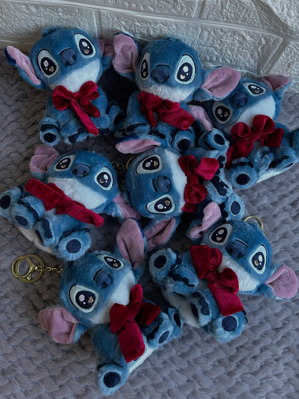 Multiple blue plush toys with red bows on a textured surface