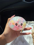 Pastel Squishy Dumpling toy beside opened yellow container