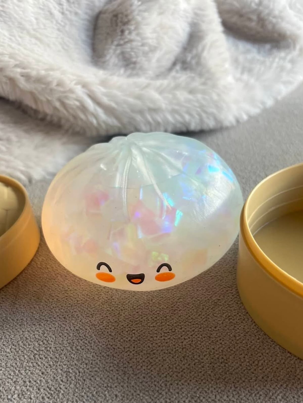 Pastel Squishy Dumpling toy with smiling face held in hand