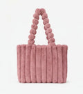 Pink fluffy handbag with pom-pom handle on a white background