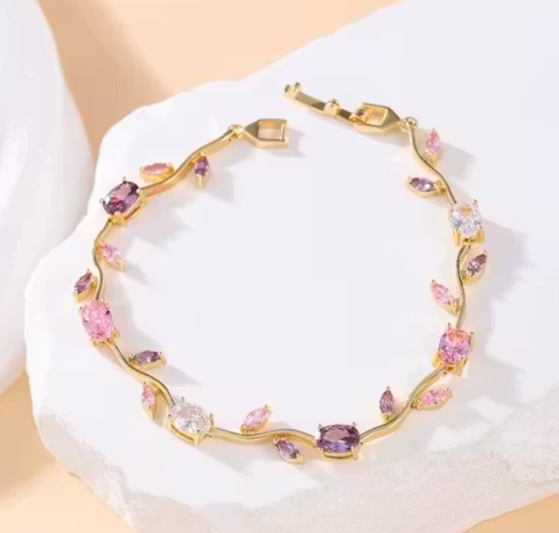 Gold bracelet with colorful stones on a white fabric background
