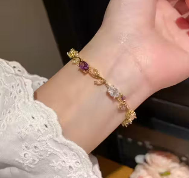 Gold bracelet with gemstones on a wrist, blurred background